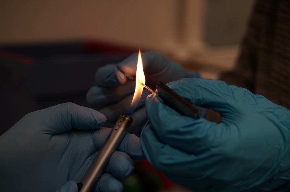 Two scientists melting a glass capillary.